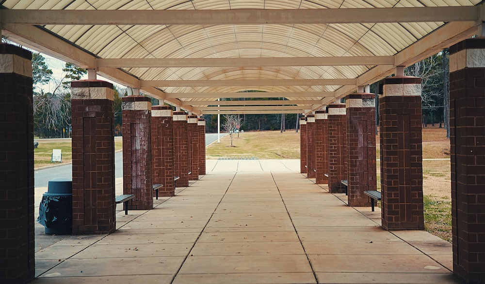a walkway lined with brick pillars and benches
